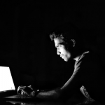 暗闇でパソコンを操作する男性